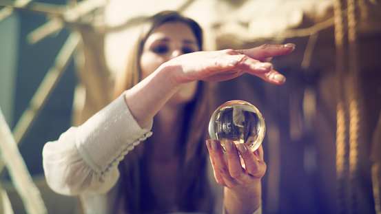 Woman fortune telling with glass sphere. Smiling and gesturing