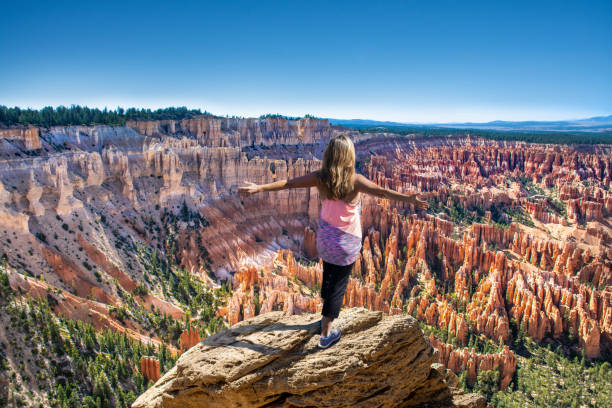 Happy woman with raised arms on mountain top in Bryce Canyon. Hiker girl on the mountain top, сoncept of freedom, victory, active lifestyle. Woman relaxing on top of the mountain looking at beautiful mountain  view. Woman with outstretched arms enjoying beautiful  scenery on hiking trip. Inspiration Point, Bryce Canyon National Park, Utah, USA bryce canyon national park stock pictures, royalty-free photos & images