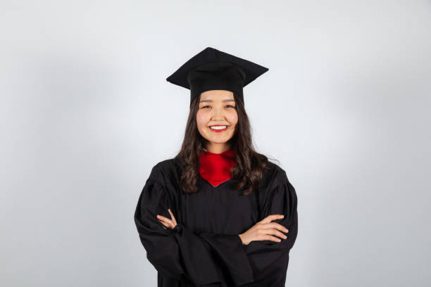 istock Smiling graduate student in mortarboard and bachelor gown on white background 1369966142