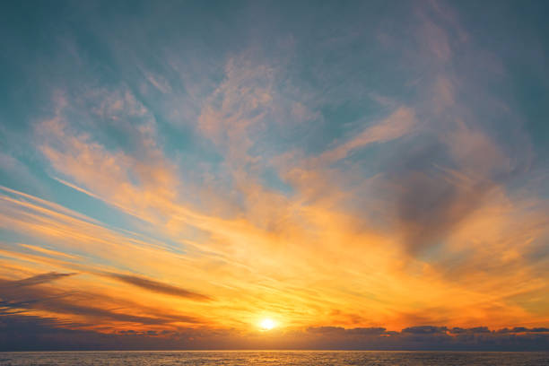 istock Magnificent view of blurry cirrus clouds with gorgeous light and a solar disk over the horizon of the sea surface of the water. 1369966465