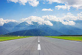 Scenic view of the runway road and mountain peaks in the clouds in the distance.