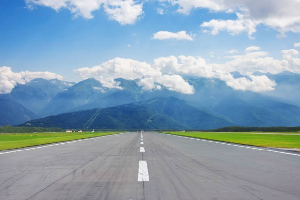 Scenic view of the runway road and mountain peaks in the clouds in the distance. Scenic view of the runway road and mountain peaks in the clouds in the distance runway stock pictures, royalty-free photos & images