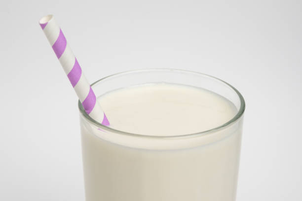 Milk glass with colored straw close-up on a white background