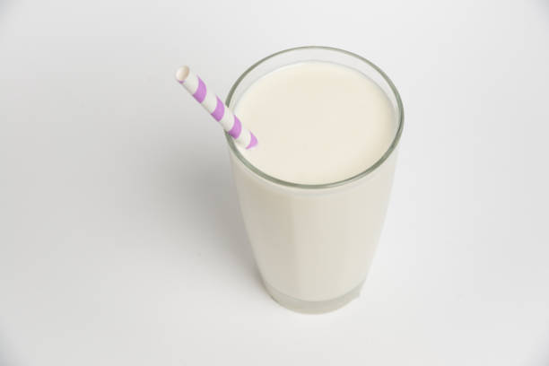 istock Top view. Milk glass with colored straw close-up on a white background 1369967628