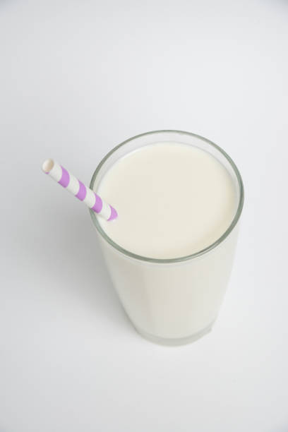 istock Top view. Milk glass with colored straw close-up on a white background 1369967634