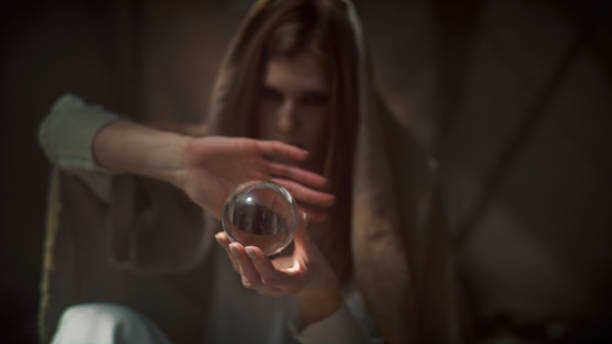 istock Mysterious female fortune teller holding glass sphere. Inside dark, desert tent 1369968778