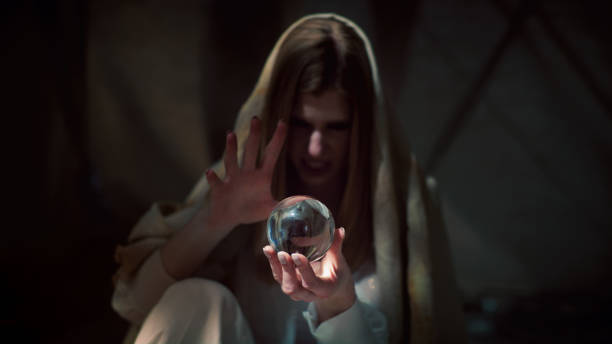 Woman fortune telling with glass sphere. Smiling and gesturing. Pink, digitally generated cosmic dust inside sphere