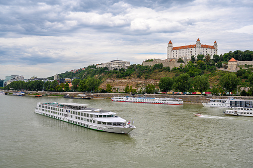 Bratislava, Slovakia - July 9, 2019: A river cruise boat passes along the River Danube in front of Bratislava Castle