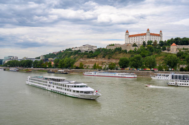 River cruise boat on Danube near Bratislava Castle Bratislava, Slovakia - July 9, 2019: A river cruise boat passes along the River Danube in front of Bratislava Castle bratislava castle bratislava castle fort stock pictures, royalty-free photos & images