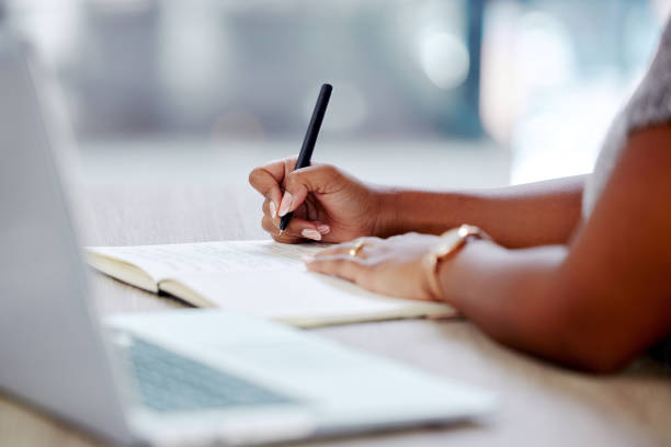 istock Shot of a businesswoman writing notes while working on her laptop 1369969766