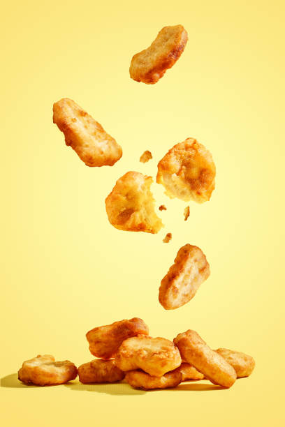 istock Flying chicken nuggets, one broken in half on yellow background 1369972378
