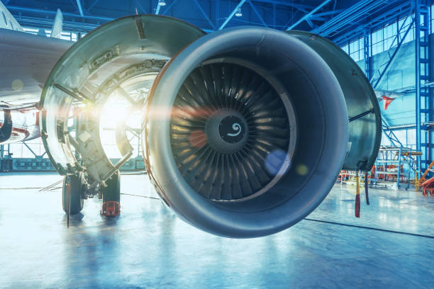 istock Jet engine with open hood covers on maintenance, illuminated by bright light from behind the hangar gate. 1369972692