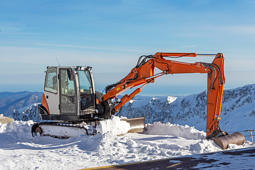 Excavator for clearing snow on tops of snowy mountains, ski resort