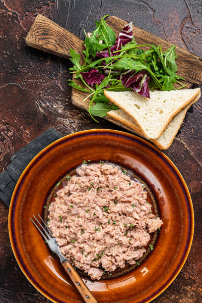 istock Tuna canned fish with bread and salad. Dark background. top view 1369972967