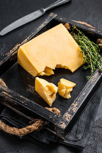 morceau de fromage à pâte dure suisse dans un plateau en bois. fond noir. vue de dessus - gouda photos et images de collection