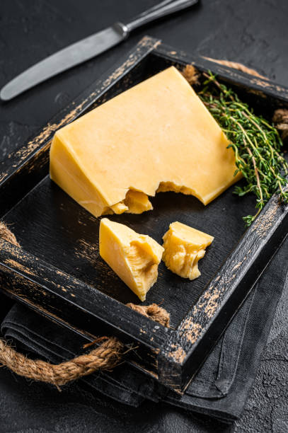 swiss hard cheese piece in wooden tray. black background. top view - gouda imagens e fotografias de stock