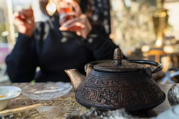 Blurred Azerbaijani woman drinking traditional tea with metal teapot