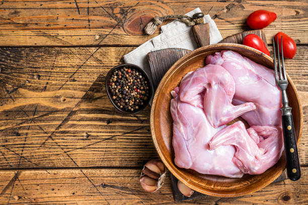 Rabbit legs uncooked in a wooden plate. Wooden background. Top view. Copy space Rabbit legs uncooked in a wooden plate. Wooden background. Top view. Copy space. rabbit game meat stock pictures, royalty-free photos & images