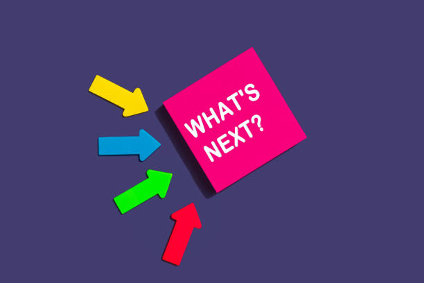 istock What's Next - concept of text on sticky note. Pink square sticky note and colorful arrows on purple background, top view 1369974420