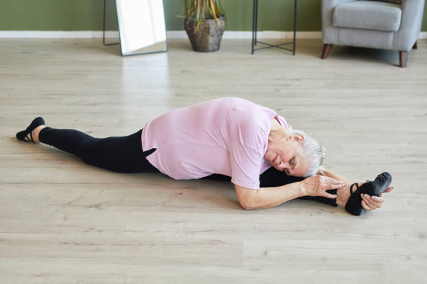 istock Active and flexible senior female keeping head on stretched leg during twine 1369974668