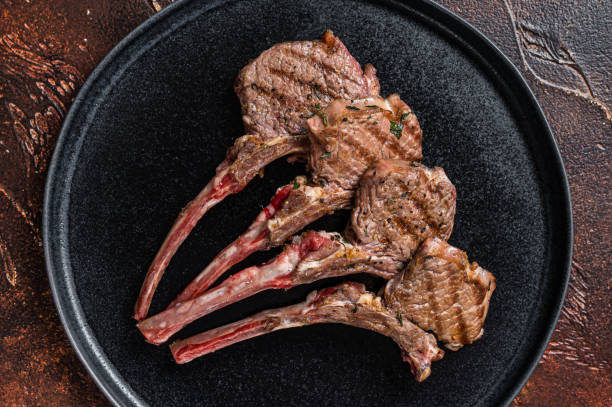 istock BBQ Grilled lamb chops steaks in a plate. Dark background. Top view 1369975128