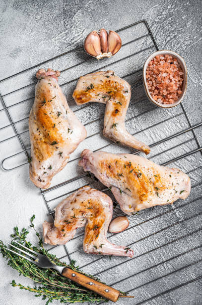 istock Baked rabbit legs on a grill with thyme. White background. Top view 1369975167