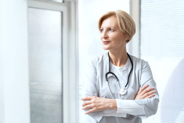 istock Confident doctor with crossed arms standing in cabinet 1369975241