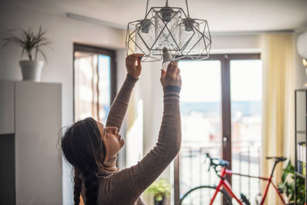 istock Woman changing energy efficient light bulb in living room. 1369976736