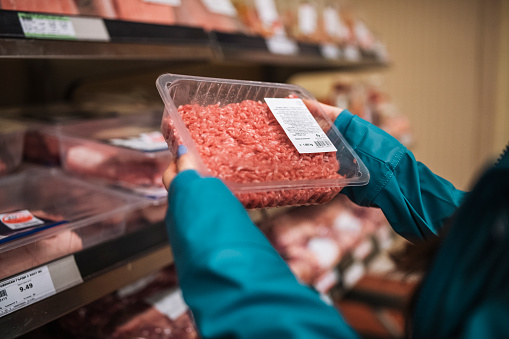 Unrecognisable woman choosing fresh minced meat in supermarket.