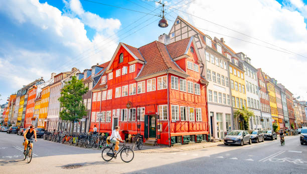 Copenhagen, Denmark - 6 August, 2021: Sunny evening in old town, people riding bikes in the city center