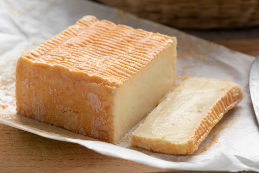 Limburger or Herve cheese and slice with a strong smell on package paper