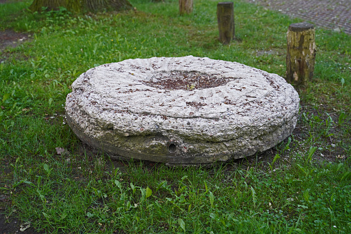 Millstone on the meadow in front of the mill. Bock windmill Südbrookmerland. Bock windmill in the north of Germany. \