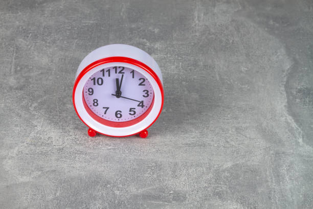 istock The red alarm clock shows the time on a gray background 1369979823