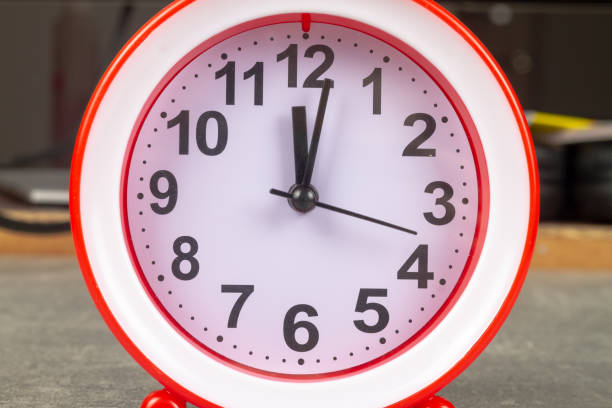 istock The red alarm clock shows the time on a gray background 1369979826