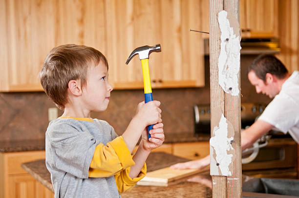 A young boy holding a hammer with both hands stock photo