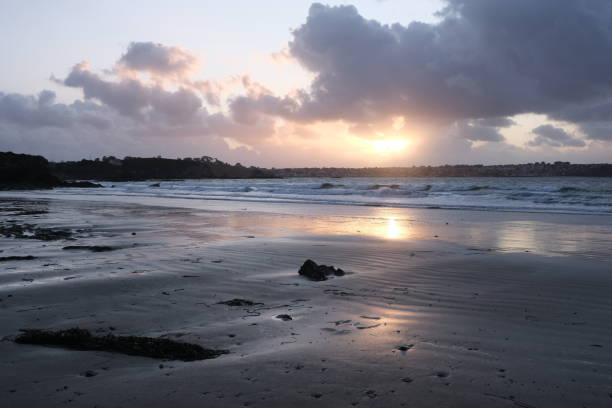 Sunset over the sea. Reflective surfaces on the sand.