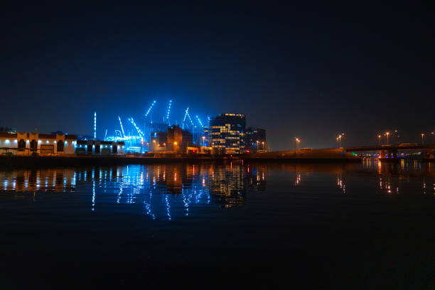 Dubai Creek with illuminated buildings and cranes - UAE
