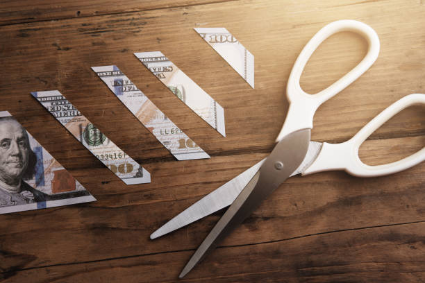 istock One hundred dollar bill is sliced into pieces with steel scissors. 1369995008