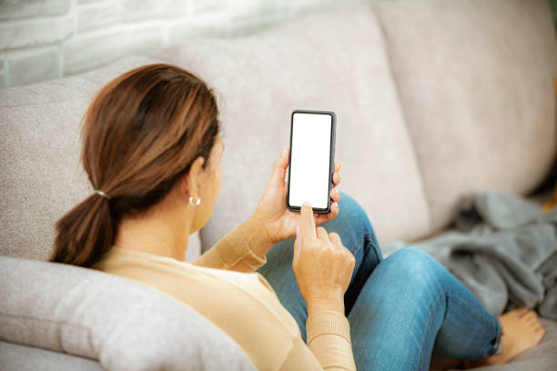 istock Woman on couch using smartphone with blank screen 1369995028