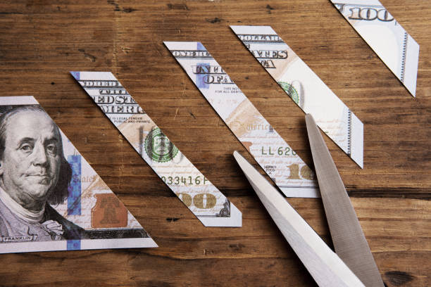 istock One hundred dollar bill is sliced into pieces with steel scissors. 1369995082