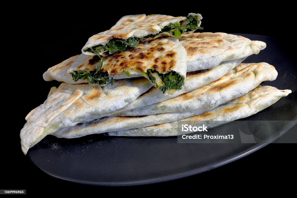 Baking of traditional Armenian food - Zhengyal bread. Bread with different greens. Cross-section of an Armenian Zhengyal bread with shallow depth of field Baking traditional Armenian dishes - Zhengyal bread. Bread with different herbs. Crosswise fracture of Armenian Zhengyal bread with shallow depth of field, selective focus, dark background Appetizer Stock Photo