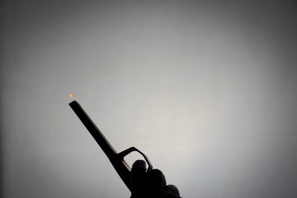 Silhouette image of person holding a kitchen gas lighter with a small flame