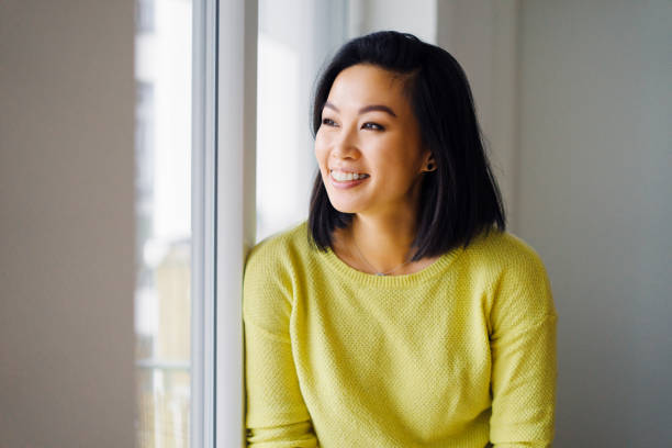 Smiling woman standing by the window at home