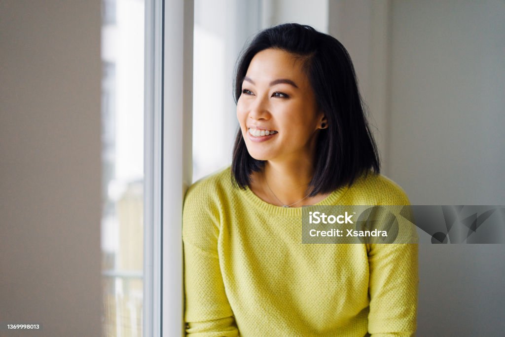Smiling woman standing by the window at home Happy woman standing by the window at home Dental Braces Stock Photo