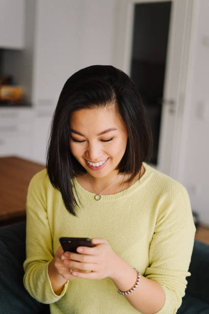 istock Smiling woman relaxing on a sofa at home and using a smartphone 1369998060