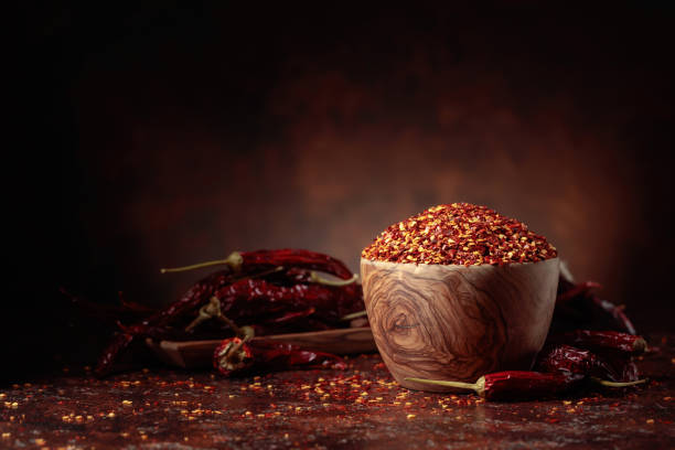 istock Chilli flakes and dried chili peppers on a brown background. 1369999783