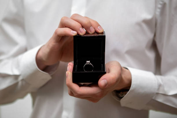 istock A young man holds in his hands a jewelry box with a diamond ring inside 1370002222