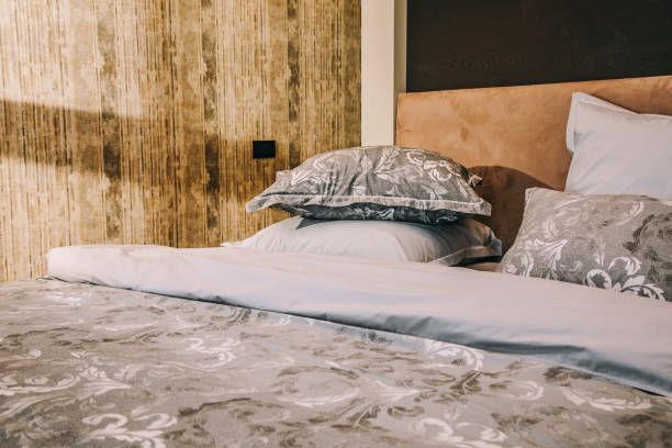 istock Low angle view of modern bed with pillows and sunbeam in bedroom 1370002368