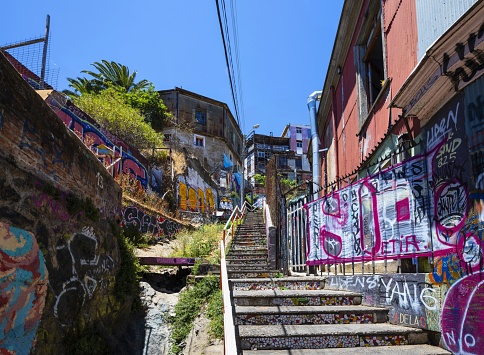 Valparaíso, Chile, December 11, 2018: View of a narrow staircase in this city of poets, bohemians, adventurers with many graffiti on the walls. The streets lead mostly downhill or uphill.