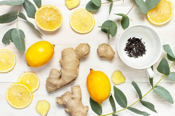 istock Fresh ginger root, cup tea with brewing inside, lemon, eucalyptus leaves on white wooden background. Flat lay, top view, copy space. Minimalistic style, seasoning, spice, ingredient for tea. 1370005261